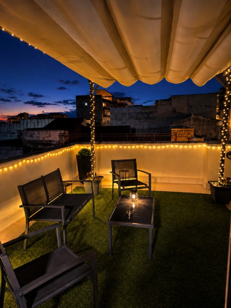 Terrazza di Aghena illuminata di sera con salottino e pergolato